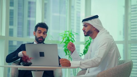 متابعة مخطط الرسم البياني،  النمو الاقتصادي والاستثمار المالي ، دراسة مشاريع جديدة،صعود وهبوط البورصة، تدقيق وتحليل بيانات المشروع،اجتماع زملاء عمل فى مقر عملهم احدهما يرتدي البدلة الرسمية يقومون بتحليل البيانات على الحاسوب المحمول