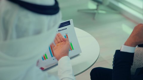 النمو الاقتصادي والاستثمار المالي ، دراسة مشاريع جديدة،صعود وهبوط البورصة، متابعة مخطط الرسم البياني، تدقيق وتحليل بيانات المشروع،اجتماع زملاء عمل فى مقر عملهم احدهما يرتدي البدلة الرسمية يقومون بتحليل البيانات على الحاسوب المحمول