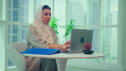 امراه عربيه خليجيه اماراتيه تقوم بتحليل البيانات على الحاسوب المحمول، متابعة مخطط الرسم البياني، تدقيق وتحليل بيانات المشروع، دراسة مشاريع جديدة، صعود وهبوط البورصة، النمو الاقتصادي والاستثمار المالي