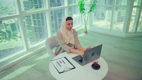 Studying new projects, economic growth and financial investment, stock market ups and downs, tracking charts, auditing and analyzing project data, an Arab Gulf Emirati woman analyzing data on a laptop