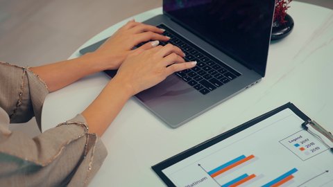 النمو الاقتصادي والاستثمار المالي ، صعود وهبوط البورصة، متابعة مخطط الرسم البياني، تدقيق وتحليل بيانات المشروع، امراه عربيه خليجيه اماراتيه تقوم بتحليل البيانات على الحاسوب المحمول، دراسة مشاريع جديدة