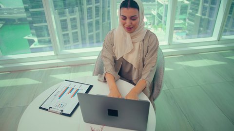 متابعة مخطط الرسم البياني، تدقيق وتحليل بيانات المشروع، امراه عربيه خليجيه اماراتيه تقوم بتحليل البيانات على الحاسوب المحمول، دراسة مشاريع جديدة، صعود وهبوط البورصة، النمو الاقتصادي والاستثمار المالي