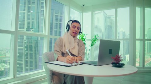 صعود وهبوط البورصة، متابعة مخطط الرسم البياني، تدقيق وتحليل بيانات المشروع، امراه عربيه خليجيه اماراتيه تقوم بتحليل البيانات على الحاسوب المحمول، دراسة مشاريع جديدة،  النمو الاقتصادي والاستثمار المالي