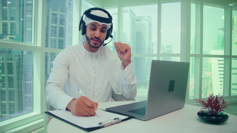 إنجاز المهام من خلال اللابتوب ،  دراسة مشاريع جديدة، إستخدام تقنيات حديثة،  رجل اماراتي يرتدي الكندورة والغترة وسماعات الرأس يقوم باجراء مكالمة فيديو عبر جهاز الحاسوب المحمول، تدوين وكتابة الملاحظات، مفهوم إدارة الأعمال، تدقيق وتحليل بيانات المشروع، النمو الاقتصادي والاستثمار المالي