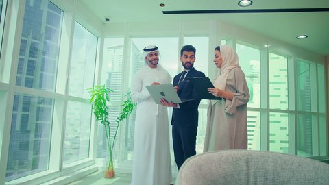 دراسة مشاريع جديدة، إستخدام تقنيات حديثة، مفهوم إدارة الأعمال، إنجاز المهام من خلال اللابتوب ،اجتماع زملاء عمل عربيين خليجيين اماراتيين مع رجل يرتدي البدلة الرسمية لتحليل وتدقيق المشروع عبر جهاز الحاسوب المحمول، النمو الاقتصادي والاستثمار المالي