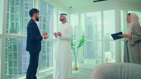 النمو الاقتصادي والاستثمار المالي، دراسة مشاريع جديدة، إستخدام تقنيات حديثة، مفهوم إدارة الأعمال، إنجاز المهام من خلال اللابتوب ،اجتماع زملاء عمل عربيين خليجيين اماراتيين مع رجل يرتدي البدلة الرسمية لتحليل وتدقيق المشروع عبر جهاز الحاسوب المحمول