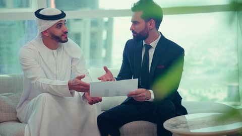 Business agreement for a new project, an Emirati Gulf Arab businessman wearing a kandura and ghutra discussing with a client wearing a formal suit, project analysis and planning, business development and problem solving, unity and teamwork, achieving company goals