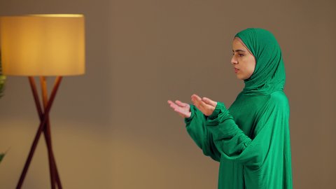 التضرع والطلب من الله، الاجتهاد في الطاعات والأدعية والأذكار, مفهوم العبادة والتقرب إلى الله, امرأة عربية خليجية إماراتية ترتدي العباءة والحجاب ترفع يديها للأعلى بتعابير الدعاء, شابة سعودية تصلي بايماءات الخشوع والطمأنينة