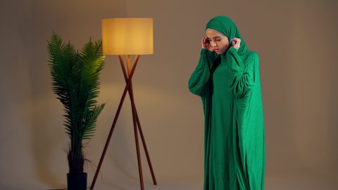 Maintaining the performance of the five daily prayers on time, striving in worship, a Saudi woman prostrating with gestures of humility and tranquility, an Arab Gulf Emirati woman wearing the abaya and hijab sitting on a prayer rug performing the obligatory prayer, the concept of the pillars of Islam and faith, drawing closer to God.