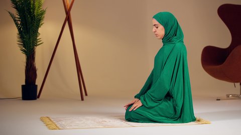 امراه عربيه خليجيه اماراتيه ترتدي العباءه والحجاب تجلس على سجادة الصلاة تقوم بأداء فريضة الصلاة، مفهوم أركان الاسلام والأيمان، التقرب الى الله ، الحفاظ على إقامة الصلوات الخمس بوقتها، الإجتهاد في العبادة، سيدة سعودية تسجد بايماءات الخشوع والطمأنينة
