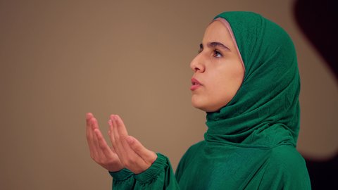 امرأة عربية خليجية إماراتية ترتدي العباءة والحجاب ترفع يديها للأعلى بتعابير الدعاء, الاجتهاد في الطاعات والأدعية والأذكار, مفهوم العبادة والتقرب إلى الله, شابة سعودية تصلي بايماءات الخشوع والطمأنينة