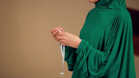 Worship, obedience, and drawing closer to God. An Emirati Arab woman wearing an abaya and hijab holds in her hand a rosary made of white beads, the concept of glorification and declaration of faith. A Saudi woman is engaged in the remembrance of God Almighty, striving in acts of worship.