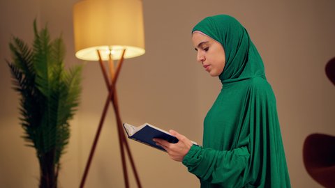 سيدة سعودية تقوم بذكر الله تعالي، مفهوم التمعن بآيات وسور القران الكريم ،الاجتهاد في العبادة، قراءة كتاب الله وحفظه وتجويده، تلاوة المصحف الشريف، امراه عربيه خليجيه اماراتيه ترتدي العباءه والحجاب تحمل بيدها القرآن