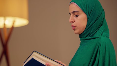 تلاوة المصحف الشريف، امراه عربيه خليجيه اماراتيه ترتدي العباءه والحجاب تحمل بيدها القرآن ، مفهوم التمعن بآيات وسور القران الكريم ،الاجتهاد في العبادة، قراءة كتاب الله وحفظه وتجويده،سيدة سعودية تقوم بذكر الله تعالي
