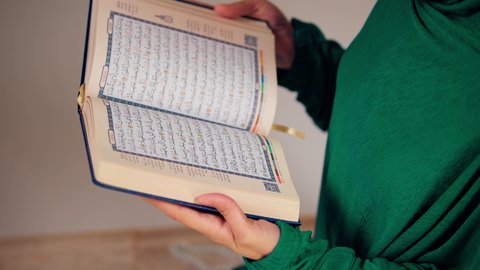 امراه عربيه خليجيه اماراتيه ترتدي العباءه والحجاب تحمل بيدها القرآن ، مفهوم الاجتهاد في العبادة، قراءة كتاب الله وحفظه وتجويده، تلاوة المصحف الشريف،سيدة سعودية تقوم بذكر الله تعالي