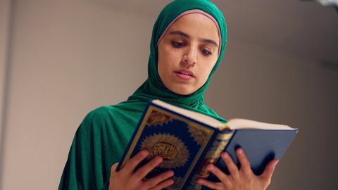 امراه عربيه خليجيه اماراتيه ترتدي العباءه والحجاب تحمل بيدها القرآن ، مفهوم الاجتهاد في العبادة، قراءة كتاب الله وحفظه وتجويده، تلاوة المصحف الشريف،سيدة سعودية تقوم بذكر الله تعالي