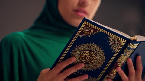 سيدة سعودية تقوم بذكر الله تعالي، مفهوم الاجتهاد في العبادة، قراءة كتاب الله وحفظه وتجويده، تلاوة المصحف الشريف، امراه عربيه خليجيه اماراتيه ترتدي العباءه والحجاب تحمل بيدها القرآن