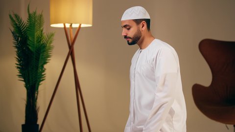 الإجتهاد في العبادة، شاب عربي خليجي اماراتي يرتدي الثوب الأبيض والطاقية يقوم بأداء فريضة الصلاة،مفهوم أركان الاسلام والأيمان،اجواء روحانية رمضانية، التقرب الى الله ، الحفاظ على إقامة الصلوات الخمس بوقتها،  الشعور بالخشوع والطمأنينة
