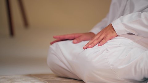 الشعور بالخشوع والطمأنينة  ، مفهوم أركان الاسلام والأيمان،اجواء روحانية رمضانية، التقرب الى الله ، الحفاظ على إقامة الصلوات الخمس بوقتها، الإجتهاد في العبادة، شاب عربي خليجي اماراتي يرتدي الثوب الأبيض والطاقية يجلس على سجاده الصلاه يقوم بأداء فريضة الصلاة