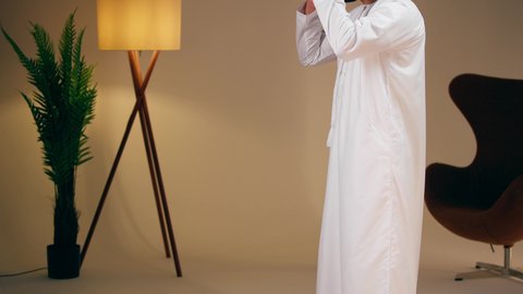 مفهوم أركان الاسلام والأيمان، التقرب الى الله ، الحفاظ على إقامة الصلوات الخمس بوقتها، الإجتهاد في العبادة، تصوير مقرب لشاب عربي خليجي اماراتي يرتدي الثوب الأبيض والطاقية يقوم بأداء فريضة الصلاة، الشعور بالخشوع والطمأنينة