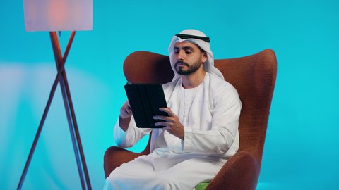 Work-related papers, noting daily tasks, an Arab Gulf Emirati man wearing a kandura and ghutrah holding white papers and a pen in his hands, a Saudi woman conducting scientific research, reading notes and information, following up on plans and projects.
