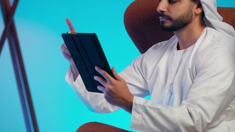 Work-related papers, noting daily tasks, an Arab Gulf Emirati man wearing a kandura and ghutrah holding white papers and a pen in his hands, a Saudi woman conducting scientific research, reading notes and information, following up on plans and projects.