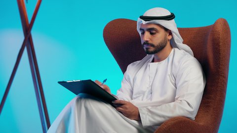 متابعة الخطط والمشاريع، أوراق خاصة بالعمل, تدوين المهام اليومية ، رجل عربي خليجي اماراتي يرتدي الكندورة والغترة  يحمل بيديه اوراق بيضاء وقلم، شابه سعوديه تقوم بالبحث العلمي، قراءة الملاحظات والمعلومات