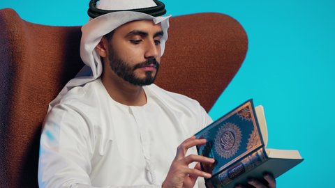 التقرب الى رب العالمين ، قراءة وحفظ القرآن الكريم،  رجل عربي خليجي اماراتي يرتدي الكندورة والغتره  يجلس على كرسي مريح يقوم بقراءة المصحف الشريف، تلاوة كتاب الله تعالى ,الاجتهاد و الخشوع في العباده