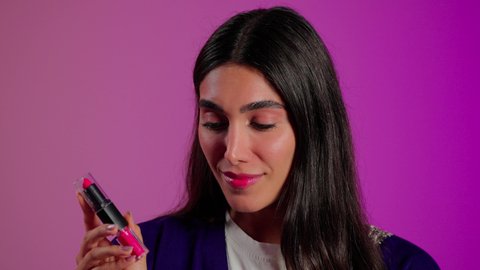 استعمال المستحضرات التجميلية, مفهوم التزين والتجمل, الترويج لمنتجات و مساحيق التجميل, العناية بالجمال والمظهر الخارجي, بورتريه مقرب لامرأة عربية خليجية سعودية ترتدي الزي الكاجوال تضع أحمر شفاه, خلفية ملونه