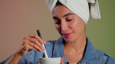 إستخدام مكونات تجميلية طبيعية، علاجات تجميل طبيعية، بورتريه مقرب لمرأة عربية خليجية سعودية تضع منشفة الرأس تمسك ماسك العسل بيديها ، مفهوم العناية والإهتمام بنضارة وتحسين البشرة ، خلفية ملونه