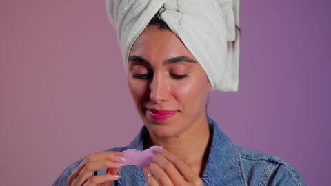 جلسات تنظيف البشرة بعمق، ماسك تنظيف المسام، بورتريه مقرب لمرأة عربية خليجية سعودية ترتدي منشفة الرأِس تضع لصقات الأنف للتخلص من الرؤوس السوداء والجلد الميت ، خلفية ملونه