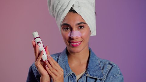 روتين العناية بالبشرة، ماسك تنظيف المسام، بورتريه مقرب لمرأة عربية خليجية سعودية ترتدي منشفة الرأِس تضع لصقات الأنف للتخلص من الرؤوس السوداء والجلد الميت، مفهوم العناية والإهتمام بنضارة وتحسين البشرة ، إستخدام أداة شفط لحب الشباب، خلفية ملونه