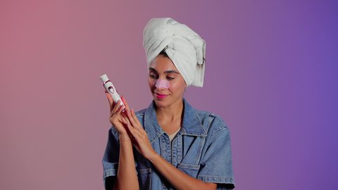 ماسك تنظيف المسام، بورتريه مقرب لمرأة عربية خليجية سعودية ترتدي منشفة الرأِس تضع لصقات الأنف للتخلص من الرؤوس السوداء والجلد الميت، مفهوم العناية والإهتمام بنضارة وتحسين البشرة ، روتين العناية بالبشرة ، إستخدام أداة شفط لحب الشباب، خلفية ملونه