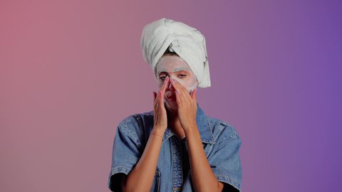 تجديد البشرة والحفاظ على نضارتها وإشراقها، خطوات تنظيف وتقشير البشرة، استخدام مكون ومستحضر تجميلي، بورتريه مقرب لامرأة عربية خليجية سعودية ترتدي منشفة الرأس  تقوم بوضع قناع على وجهها، خلفية ملونه