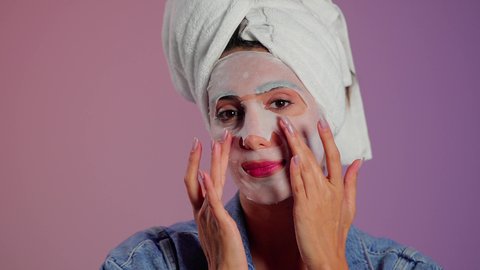 تحسين ملمس البشرة والحفاظ على جمالها الطبيعي، خطوات تنظيف وتقشير البشرة، استخدام مكون ومستحضر تجميلي، بورتريه مقرب لامرأة عربية خليجية سعودية ترتدي منشفة الرأس  تقوم بوضع قناع على وجهها، خلفية ملونه