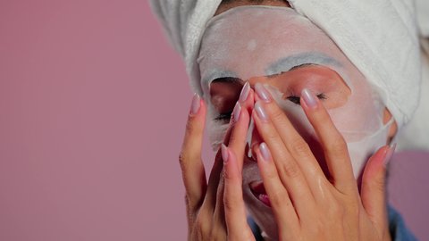 خطوات تنظيف وتقشير البشرة، تحسين ملمس البشرة والحفاظ على جمالها الطبيعي، استخدام مكون ومستحضر تجميلي، بورتريه مقرب لامرأة عربية خليجية سعودية ترتدي منشفة الرأس  تقوم بوضع قناع على وجهها، خلفية ملونه