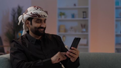 رجل عربي يمني يرتدي القميص والازار مع العمامة  يجلس ويحمل الهاتف المحمول، تبادل الأحاديث و الأخبار الجيدة، إيماءات السعادة بالتواصل مع الأصدقاء والأقارب، تمثيل الرجولة العربية الأصيلة،  المحافظة على اللباس التقليدي ، استخدام جهاز تقني حديث ومتطور، مفهوم الهيبة والاناقة