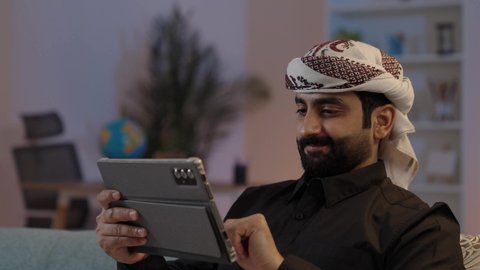 رجل عربي يمني يرتدي القميص والازار مع العمامة يمسك بيده جهاز تابلت بإيماءات الجدية والتركيز،  استخدام الجهاز اللوحي في إنجاز مهام العمل، تصفح تطبيقات التواصل الاجتماعي، استعمال التكنولوجيا الحديثة، الدردشة والتحدث مع الاصدقاء عبر الانترنت