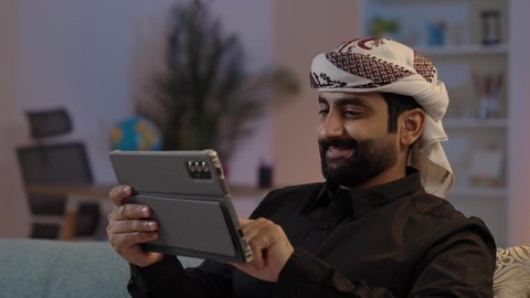 رجل عربي يمني يرتدي القميص والازار مع العمامة يمسك بيده جهاز تابلت بإيماءات الجدية والتركيز، تصفح تطبيقات التواصل الاجتماعي، استخدام الجهاز اللوحي في إنجاز مهام العمل، استعمال التكنولوجيا الحديثة،  الدردشة والتحدث مع الاصدقاء عبر الانترنت