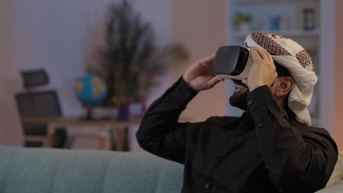 رجل يمني يرتدي القميص والازار مع العمامة ونظارة الواقع الافتراضي ثلاثية الأبعاد، التفاعل ومحاكاة العالم الخيالي، رجل عربي يمني يقوم بمشاهدة أفلام عبر نظارات الواقع الإفتراضي يشير بإصبعه لشيء ما,  محاكاة العالم الافتراضي، استخدام تقنية في آر ثلاثية الابعاد