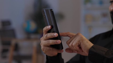 رجل عربي يمني يرتدي القميص والازار مع العمامة يجلس ويحمل الهاتف المحمول، تصفح البرامج والتسوق الالكتروني، تبادل الأحاديث و الأخبار الجيدة، إيماءات السعادة بالتواصل مع الأصدقاء والأقارب، تمثيل الرجولة العربية الأصيلة، المحافظة على اللباس التقليدي ، مفهوم الهيبة والاناقة