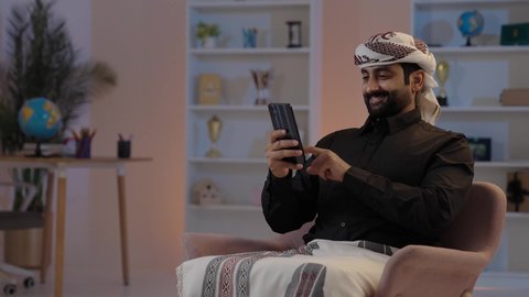 رجل عربي يمني يرتدي القميص والمعوز يجلس ويحمل الهاتف المحمول، الدردشة مع الأهل والأصدقاء، تبادل الأحاديث و الأخبار الجيدة، إيماءات السعادة بالتواصل مع الأصدقاء والأقارب، تمثيل الرجولة العربية الأصيلة،  المحافظة على اللباس التقليدي ، مفهوم الهيبة والاناقة