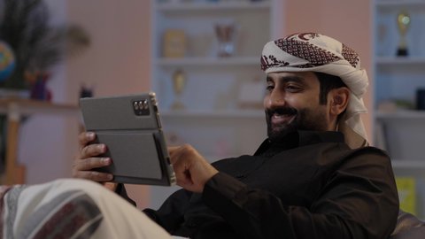 رجل عربي يمني يرتدي القميص والازار مع العمامة يمسك بيده جهاز تابلت بإيماءات الجدية والتركيز إدارة شؤون الأعمال وتنظيمها عبر الاجهزة التقنية، استعمال التكنولوجيا الحديثة، تصفح تطبيقات التواصل الاجتماعي، استخدام الجهاز اللوحي في إنجاز مهام العمل،