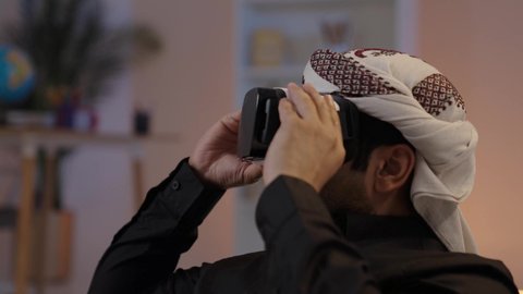 رجل عربي يمني يقوم بمشاهدة أفلام عبر نظارات الواقع الإفتراضي، رجل يمني يرتدي القميص والازار مع العمامة ونظارة الواقع الافتراضي ثلاثية الأبعاد محاكاة العالم الافتراضي، استخدام تقنية في آر ثلاثية الابعاد، المتعة و التسلية بمشاهدة الأفلام، التفاعل والاندماج مع العالم الخيالي
