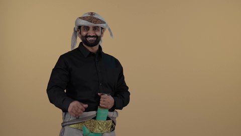 رجل عربي يمني مبتسم يرتدي القميص والازار مع العمامة والجنبية يرفع أصبعه الابهام بعلامة الجودة, السرور والفرح بتحقيق الاهداف و نيل المراد، الاعجاب والقبول والموافقة,   حركة يد وايماءات وجه تدل على الإعجاب والموافقة، خلفية بيج