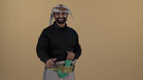رجل عربي يمني مبتسم يرتدي القميص والازار مع العمامة والجنبية يرفع أصبعه الابهام بعلامة الجودة, حركة يد وايماءات وجه تدل على الإعجاب والموافقة، السرور والفرح بتحقيق الاهداف و نيل المراد، الاعجاب والقبول والموافقة,   خلفية بيج