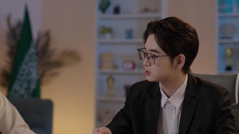 استضافة رجال الاعمال الاجانب في المملكة العربية السعودية، اعداد تقارير العمل، تبادل الخبرات والمعرفة بين البلاد، رجل عربي خليجي سعودي يرتدي الزي التقليدي مع شاب صيني يرتدي البدلة الرسمية يقومان بمناقشة المشاريع، المناقشة في اهداف الشركة