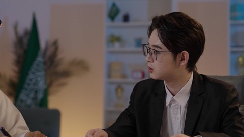 اعداد تقارير العمل، تبادل الخبرات والمعرفة بين البلاد، استضافة رجال الاعمال الاجانب في المملكة العربية السعودية، رجل عربي خليجي سعودي يرتدي الزي التقليدي مع شاب صيني يرتدي البدلة الرسمية يقومان بمناقشة المشاريع، المناقشة في اهداف الشركة