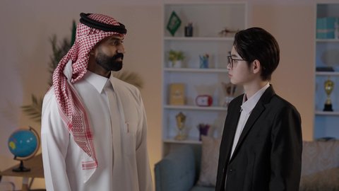 الوقوف بأيدي متقاطعة والنظر إلى الكاميرا بايماءات السعادة والسرور، استضافة رجال الاعمال الاجانب في المملكة العربية السعودية، تبادل الخبرات والمعرفة بين البلاد، رجل عربي خليجي سعودي يرتدي الزي التقليدي يقف مع شاب صيني يرتدي البدلة الرسمية