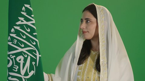 , chromaCelebrating national holidays, traditional folk costumes, Saudi National Day, September 23, Flag Day, March 11, a close-up portrait of a smiling Saudi Arabian Gulf woman wearing a sheila and nashal, holding the Kingdom's flag with gestures of pride, wearing Eastern Province dress, green background